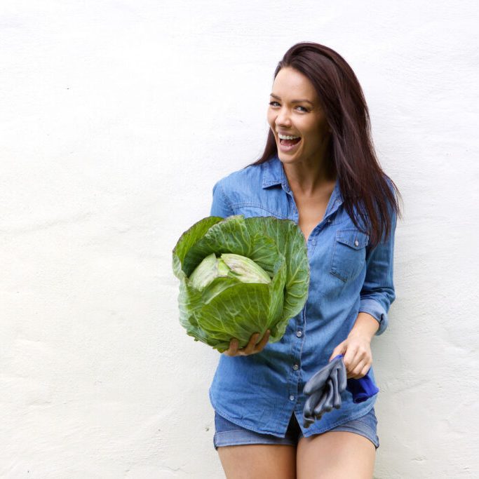 Portrait of a smiling young woman holding cabbage