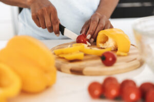 Close up of a afro american woman chopping vegetables to make a salad at the kitchen